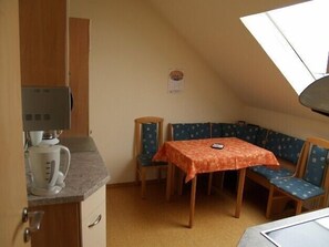 A small, cozy kitchen with a coffee maker, a table with a tablecloth, and a bench.