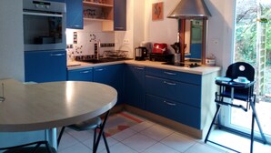 Cucina compatta con mobili blu, forno integrato, piano cottura e un'ampia finestra.