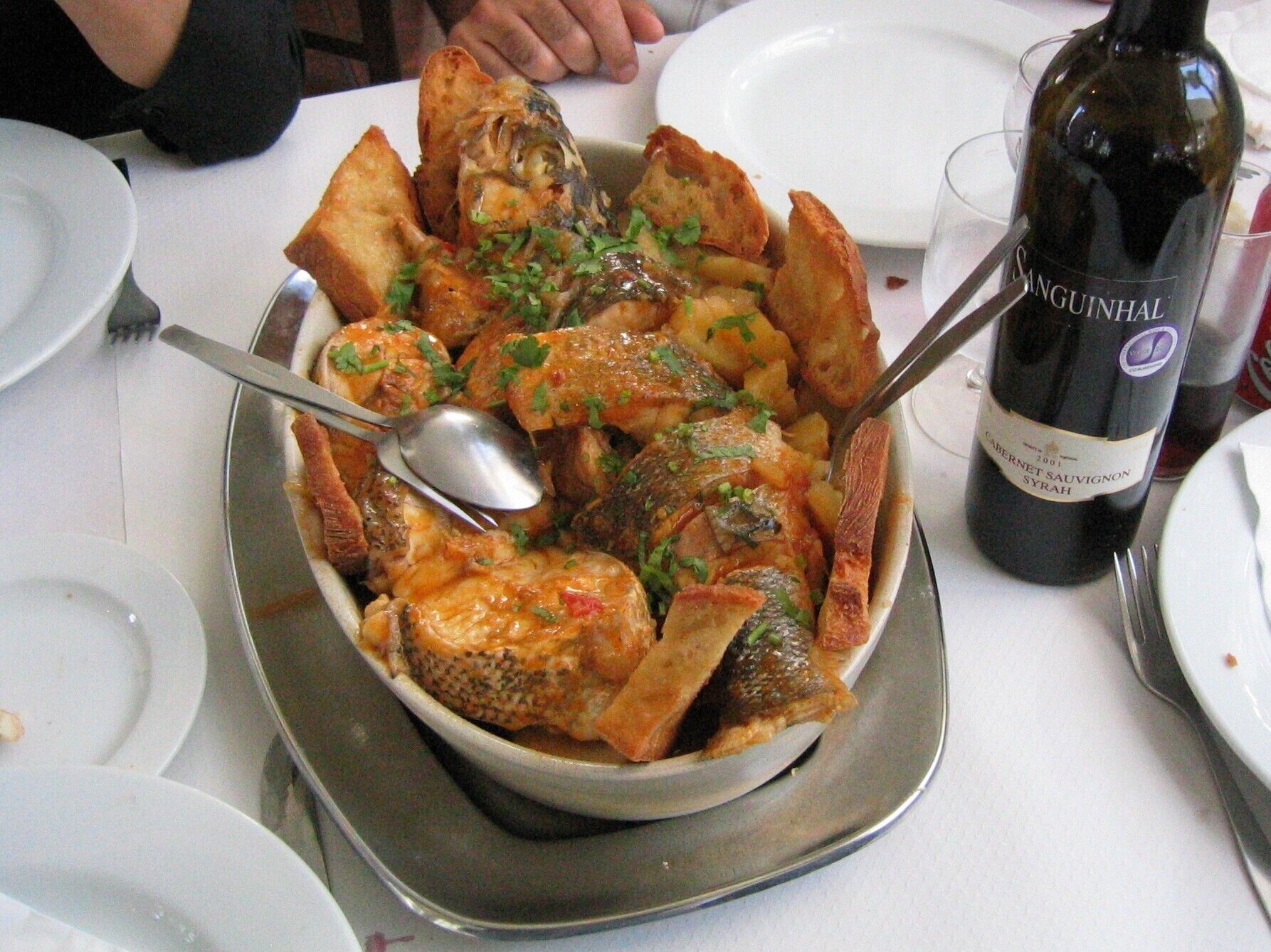Un piatto di pesce con una bottiglia di vino su un tavolo.