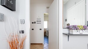 A hallway with a white door, a wall-mounted telephone, and a welcome sign. - THE SUNRISE GUEST HOUSE -  CONFORT & EASY (VARENNA)