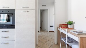 A kitchen with a stove, cabinets, and a dining area with a chair and table. - THE SUNRISE GUEST HOUSE -  CONFORT & EASY (VARENNA)