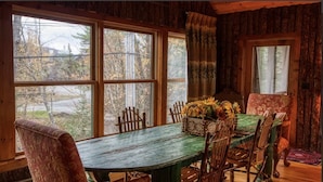 A rustic wooden cabin with a large dining table set for four, surrounded by wooden chairs.