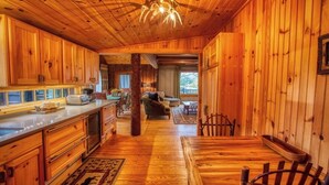 A wooden cabin interior with a kitchen, dining area, and living room.