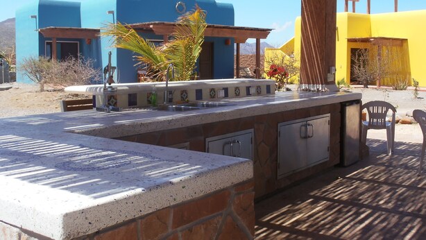 An outdoor bar area with a stone countertop, a sink, and a grill.