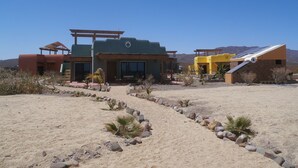 Un bâtiment de style désertique comprenant plusieurs pièces, un patio couvert et un panneau solaire.