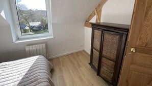 A bedroom with a bed, a window, a radiator, and a wooden cabinet. - Apartment 1ST Floor, SEA View (Paimpol)