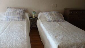 A room with two single beds, each with a plaid pillow and a white blanket. There is a small table with a lamp between the beds. - Quiet house between countryside and sea surrounded by green setting (Rouillé)