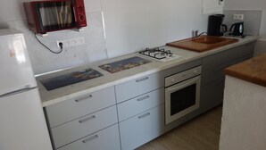 A compact kitchen with a microwave, gas stove, sink, and a small refrigerator. - Quiet house between countryside and sea surrounded by green setting (Rouillé)