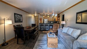 A cozy living room with a dining area, a kitchen, and a large window. - Luxury Condo w/ FREE WiFi, Parking, Heated Pool, Hot Tubs, Skier Shuttles (Avon)