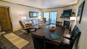 A spacious living room with a large wooden dining table, leather recliner chairs, a sofa, and a fireplace. - Luxury Condo w/ FREE WiFi, Parking, Heated Pool, Hot Tubs, Skier Shuttles (Avon)