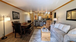 A cozy living room with a sofa, coffee table, and dining area with chairs and a table.