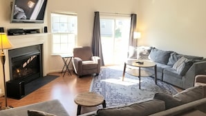 Una sala de estar con chimenea, televisor, sofá, sillón y mesa de centro.