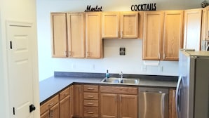 Una cocina con armarios de madera, un lavavajillas de acero inoxidable y una encimera con un fregadero.