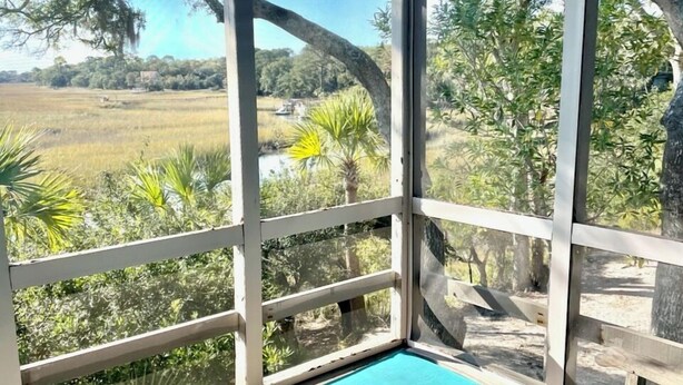 Un espace extérieur abrité, aménagé avec du mobilier en bois et offrant une vue sur un paysage naturel.
