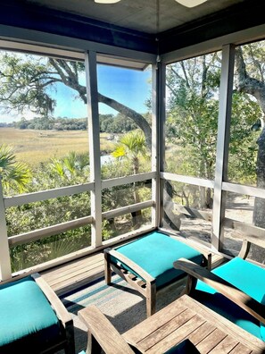 A covered outdoor seating area with wooden furniture and a view of a natural landscape.