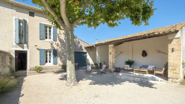 A courtyard with a building featuring blue shutters, a covered seating area with outdoor furniture, and a tree providing shade. - MAS OF VILLAGE IN JONQUERETTES NEAR AVIGNON (Jonquerettes)