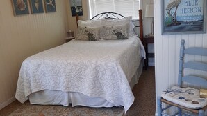 A bedroom with a bed, a chair, a rug, and wall art. - 'The Captain's Cottage' on Lake Hamilton (Hot Springs)
