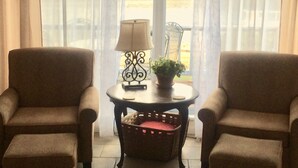 A room with two armchairs, a small table with a lamp and a plant, and a basket on the floor. - 'The Captain's Cottage' on Lake Hamilton (Hot Springs)