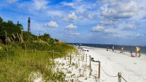 A beach with a lighthouse, sandy shore, and people relaxing.