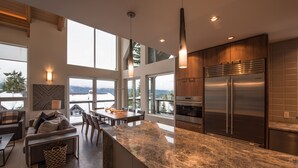 A modern kitchen with a large island, stainless steel appliances, and a view of the outdoors. - TRUE ski in/out. ski_bike_hike to BOTH Gondolas-Pvt HotTub VIEWS-walk everywhere (Whistler)