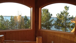 A wooden cabin with large windows overlooking a lake and trees. - Private, Exclusive Lodge on Woman Lake with Beautiful Views (Longville)