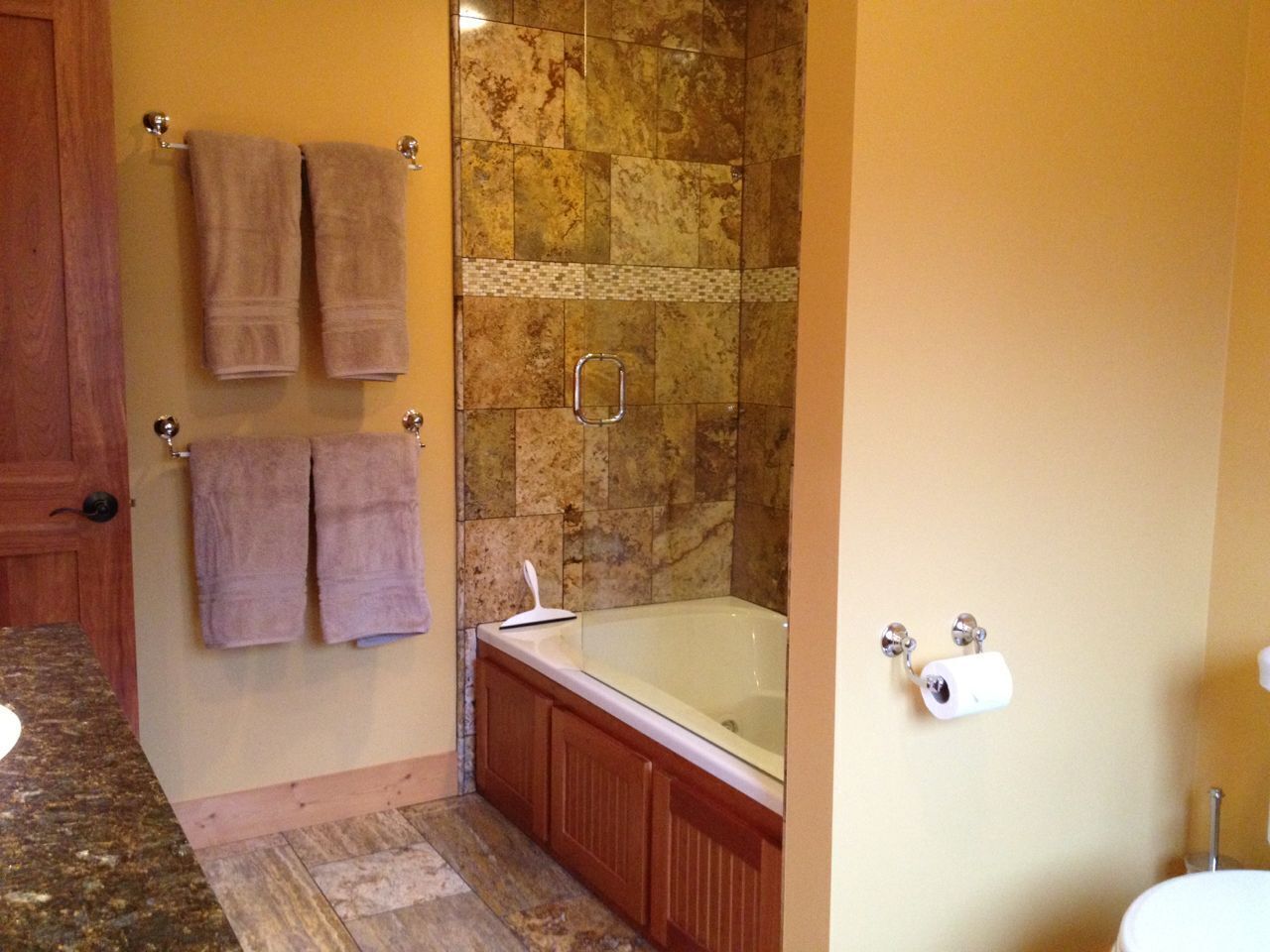 A bathroom with a bathtub, a shower, and a toilet. There are towels hanging on the wall.