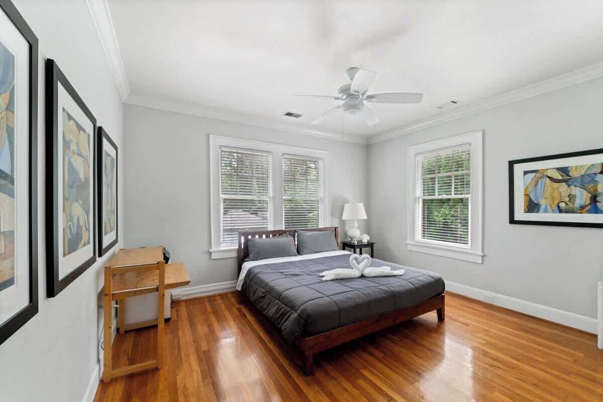 A bedroom with a bed, a ceiling fan, and framed artwork on the walls.