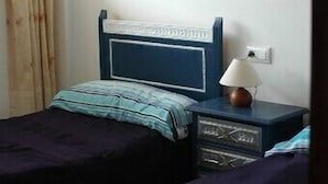 Une chambre avec deux lits, une table de chevet avec une lampe et une fenêtre avec des rideaux.