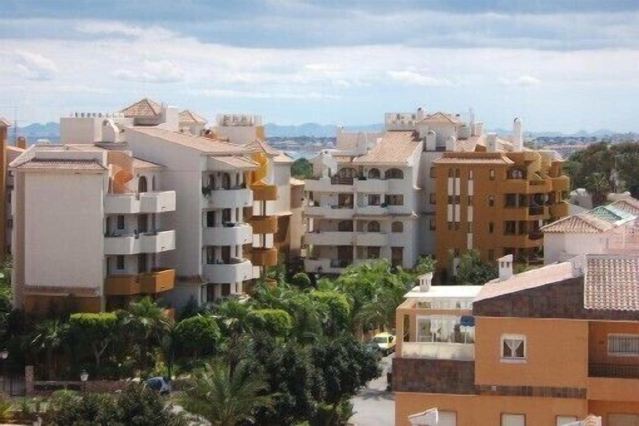 A residential area with multi-story buildings, balconies, and a clear sky.