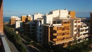 Un quartier résidentiel situé sur la côte, avec des immeubles à plusieurs étages, dont certains sont dotés de balcons, et offrant une vue dégagée sur la mer.