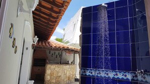 A courtyard with a stone wall, a tiled roof, and a blue-tiled entrance. - Guarujá, Pernambuco Beach, a 3-minute walk from the beach. A paradise on the beach! (Balneario Praia do Pernambuco)