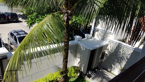 A residential area with a white building, a palm tree, and parked cars. - Guarujá, Pernambuco Beach, a 3-minute walk from the beach. A paradise on the beach! (Balneario Praia do Pernambuco)