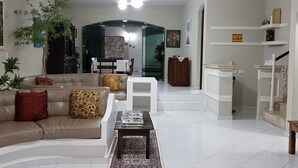 A living room with a sofa, coffee table, and a dining area with a table and chairs. - Guarujá, Pernambuco Beach, a 3-minute walk from the beach. A paradise on the beach! (Balneario Praia do Pernambuco)