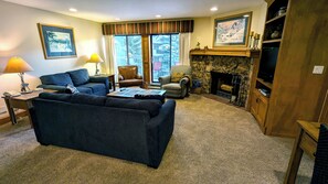 Un salon avec un canapé, des fauteuils, une cheminée et une grande fenêtre.