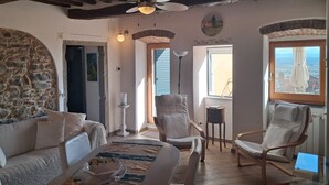 A cozy living room with a stone wall, a ceiling fan, a fireplace, and a view of the countryside. - La Terrazza sulla Valle, with private terrace overlooking the valley! (Cortona)