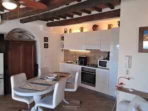 A modern kitchen with white cabinets, a dining table with chairs, a wooden ceiling, and a small dining area.