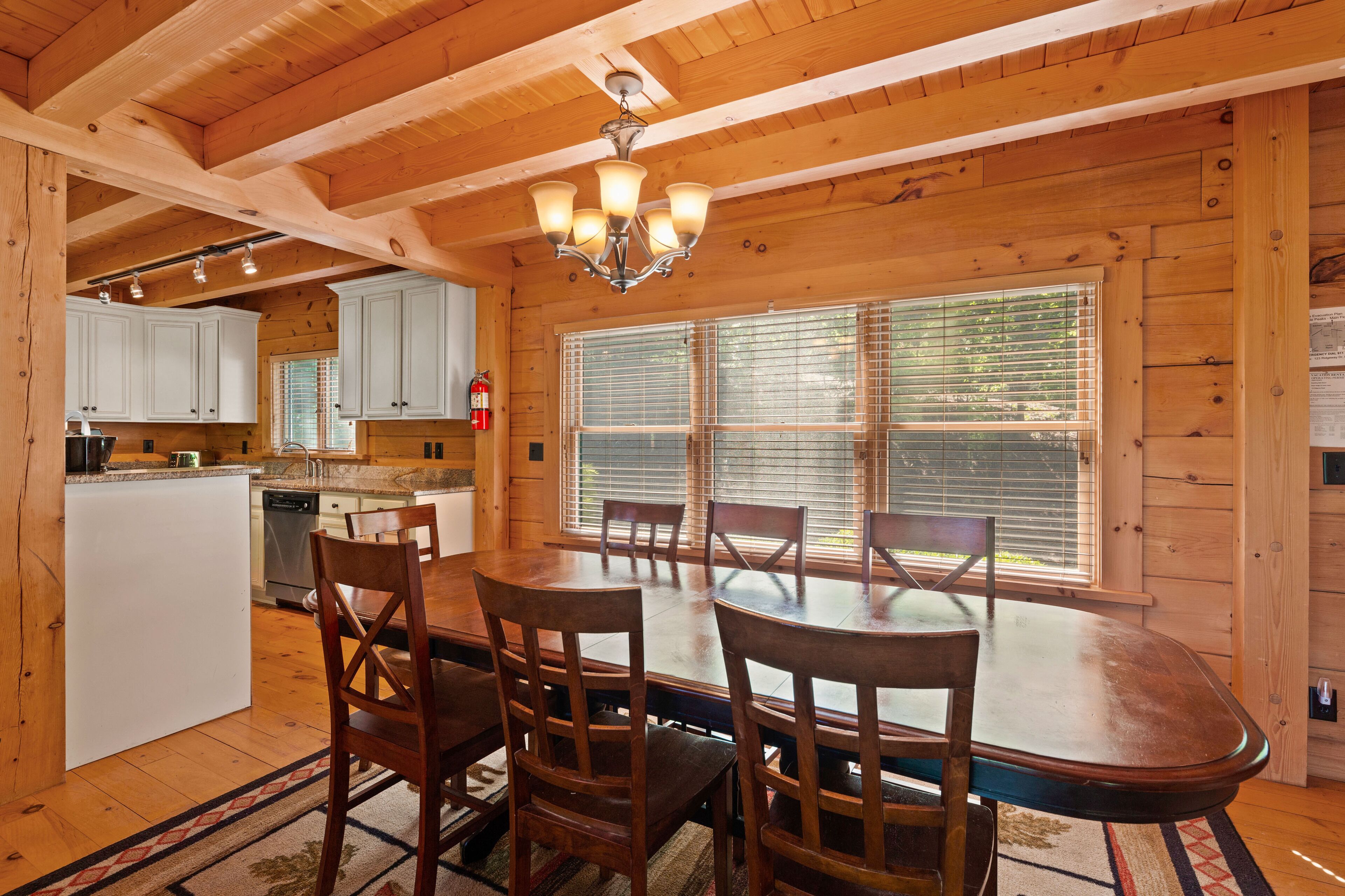 A wooden interior with a dining area, kitchen, and large windows.