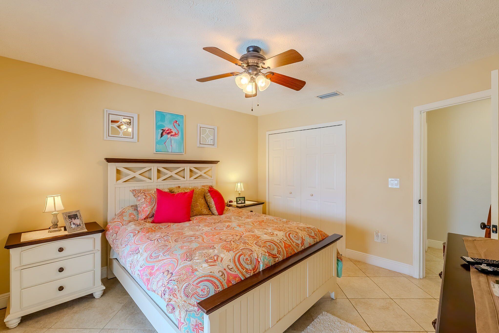 A bedroom with a bed, nightstands, a ceiling fan, and a door.