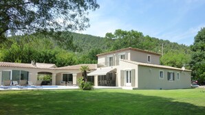 Una casa a due piani con piscina, patio coperto e prato curato.