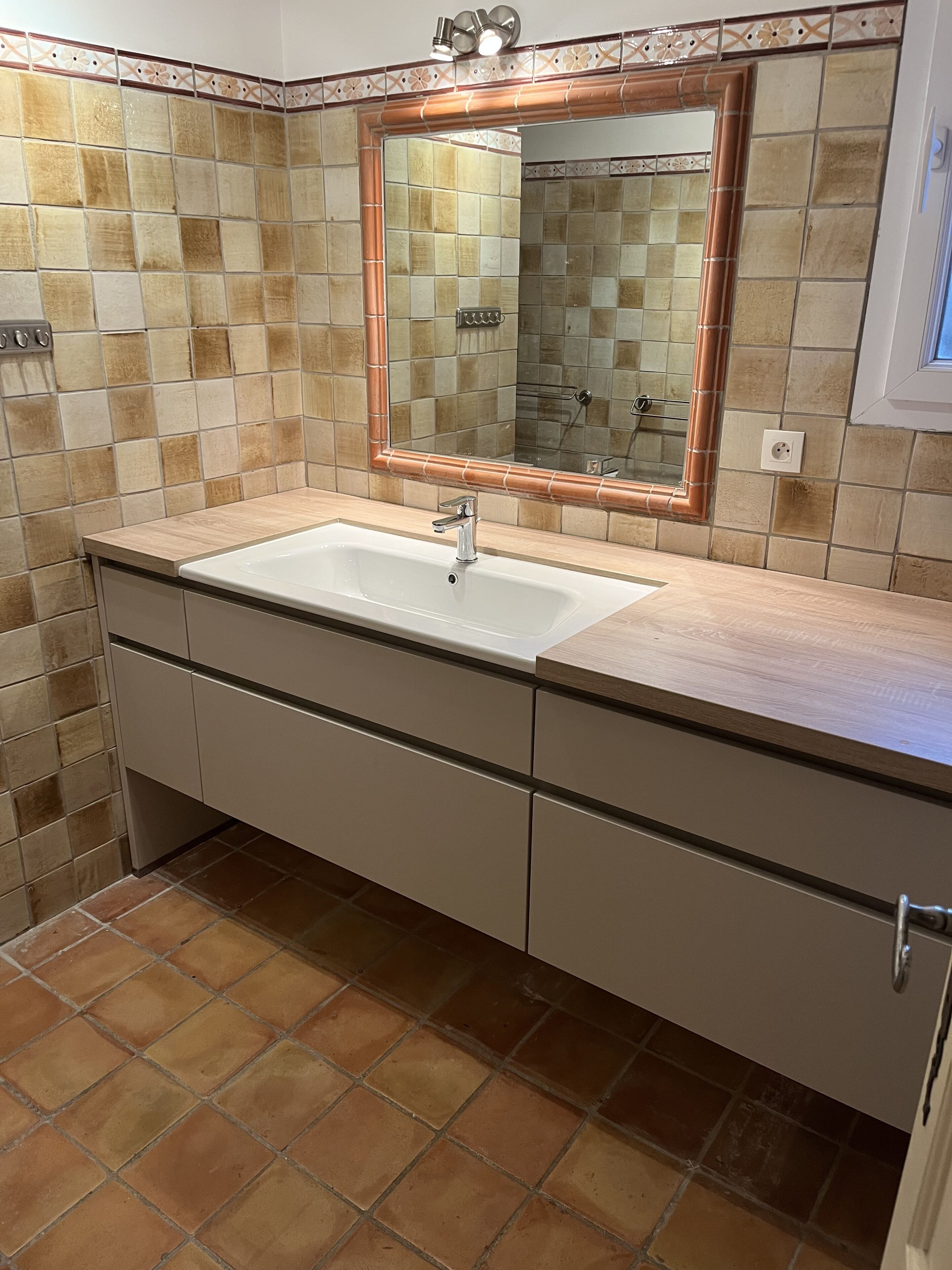 Un baño con lavamanos blanco, tuberías de cobre y un espejo.