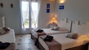 Habitación de hotel con dos camas, una ventana con cortinas translúcidas, una mesita de noche con lámpara y un aire acondicionado de pared.