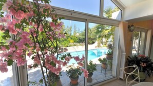 A room with large glass doors leading to a pool area, potted plants, and a chair.