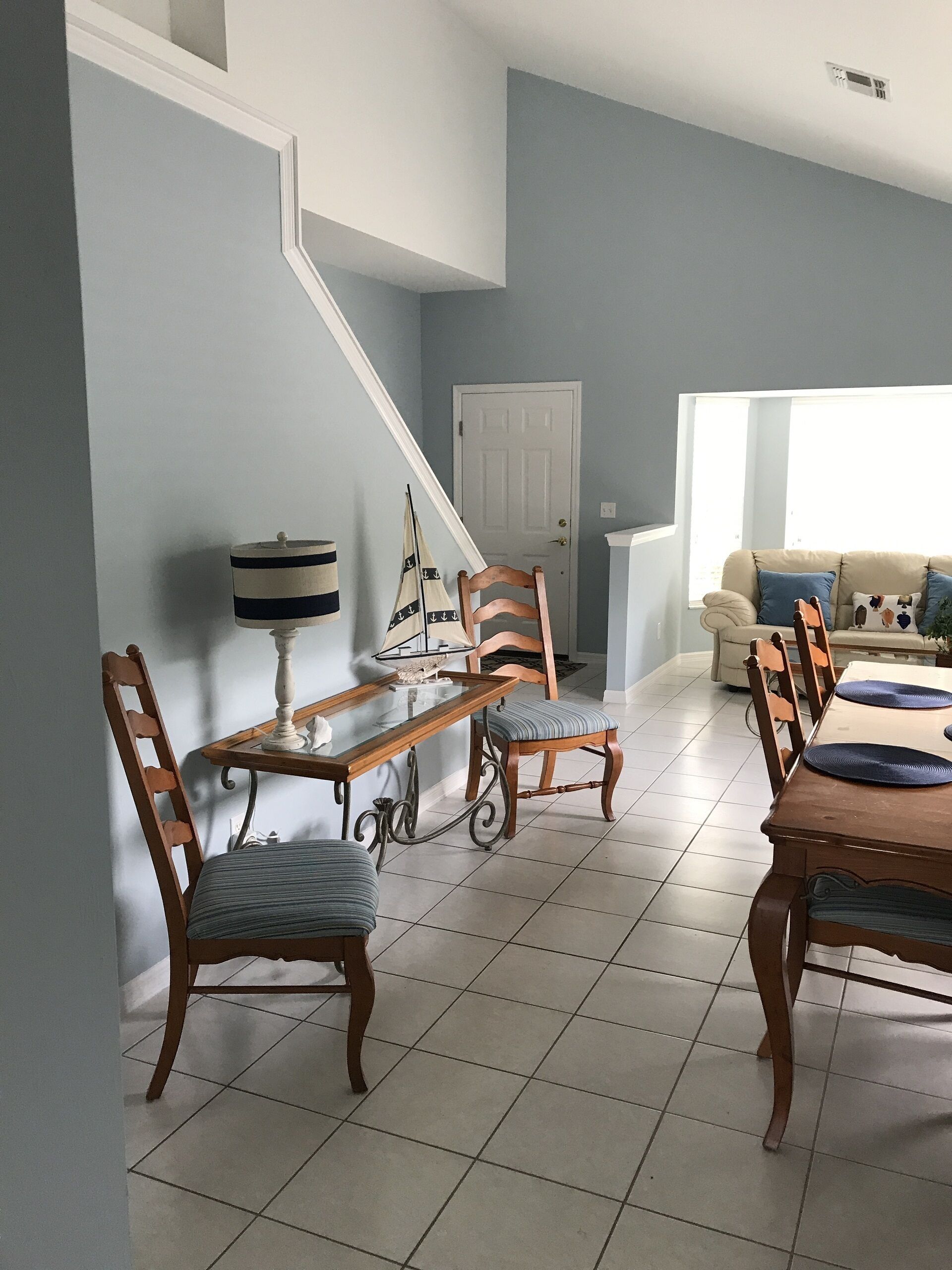 A dining area with a wooden table and chairs, a staircase, and a sofa in the background.