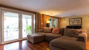 A living room with a sectional sofa, a glass door leading to an outdoor patio, and a framed picture on the wall. - Waterfront Property with a resort style backyard and Heated Pool in Miami (Miami)