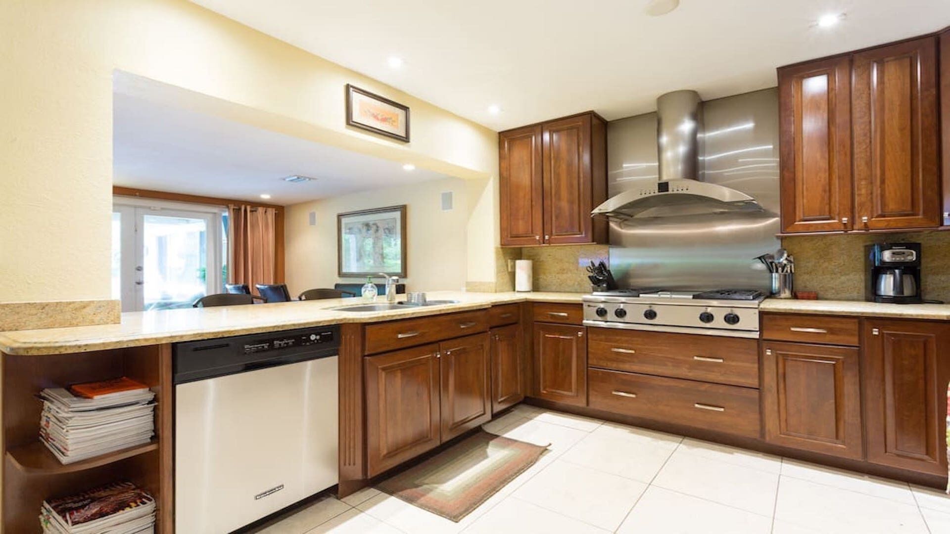 Una cocina moderna con gabinetes de madera, una campana extractora de acero inoxidable, un lavavajillas y una cafetera.