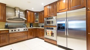 A modern kitchen with wooden cabinets, stainless steel appliances, and a gas stove. - Waterfront Property with a resort style backyard and Heated Pool in Miami (Miami)