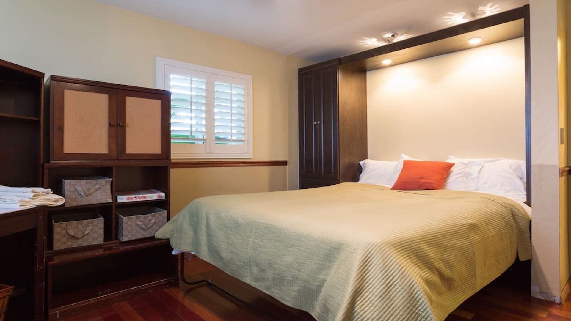 Un dormitorio con cama, armario y ventana.