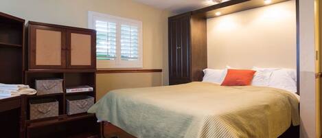 Un dormitorio con cama, armario y ventana.