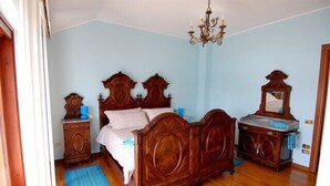 A bedroom with a wooden bed, a dresser, a mirror, and a chandelier.
