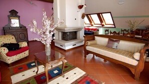 A living room with a fireplace, a sofa, a chair, and a table with a vase of flowers.